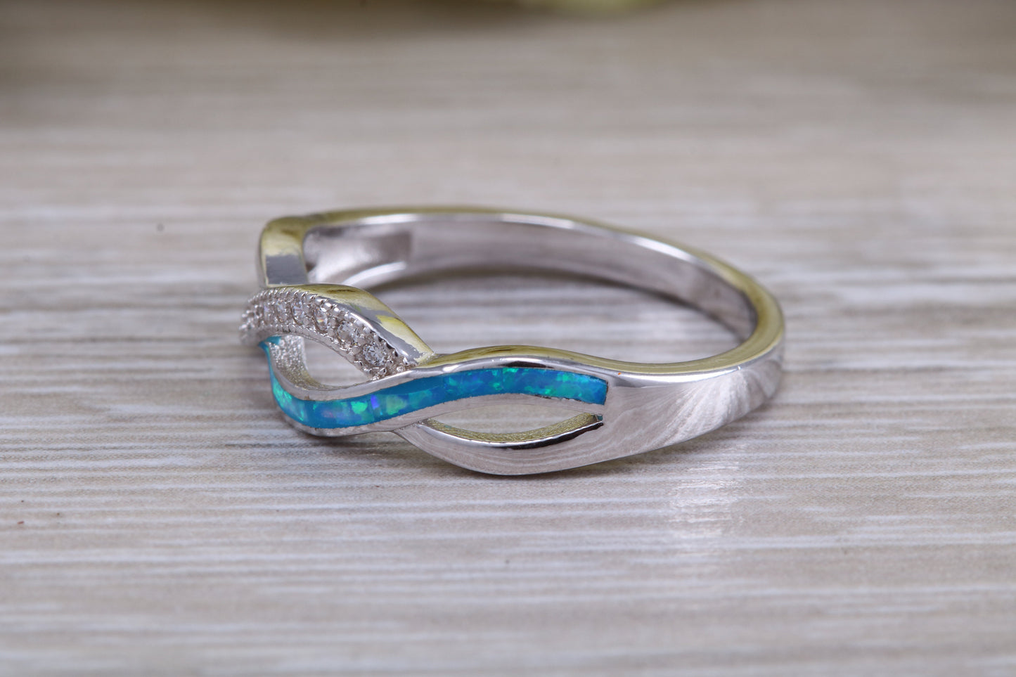 Fiery Blue Opal and cubic zirconia set cross over ring, solid sterling silver ring further rhodium plated for that platinum look