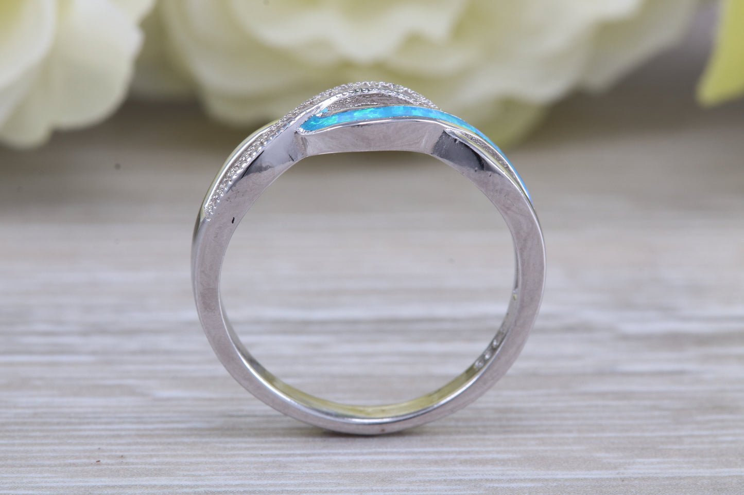 Fiery Blue Opal and cubic zirconia set cross over ring, solid sterling silver ring further rhodium plated for that platinum look