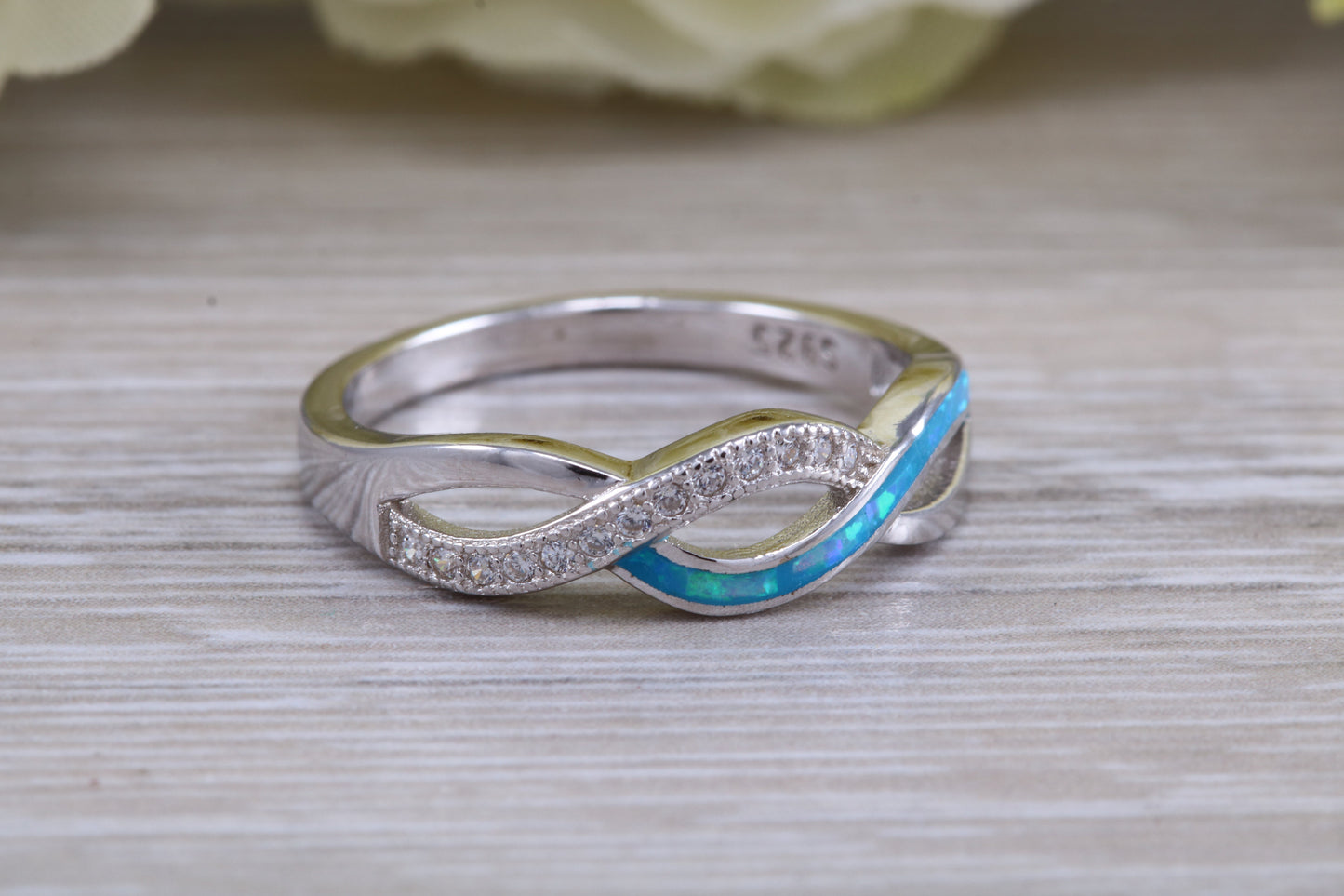 Fiery Blue Opal and cubic zirconia set cross over ring, solid sterling silver ring further rhodium plated for that platinum look