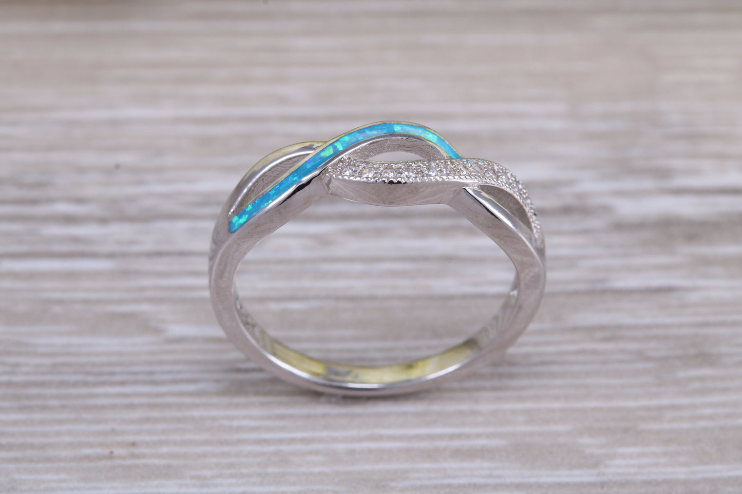 Fiery Blue Opal and cubic zirconia set cross over ring, solid sterling silver ring further rhodium plated for that platinum look