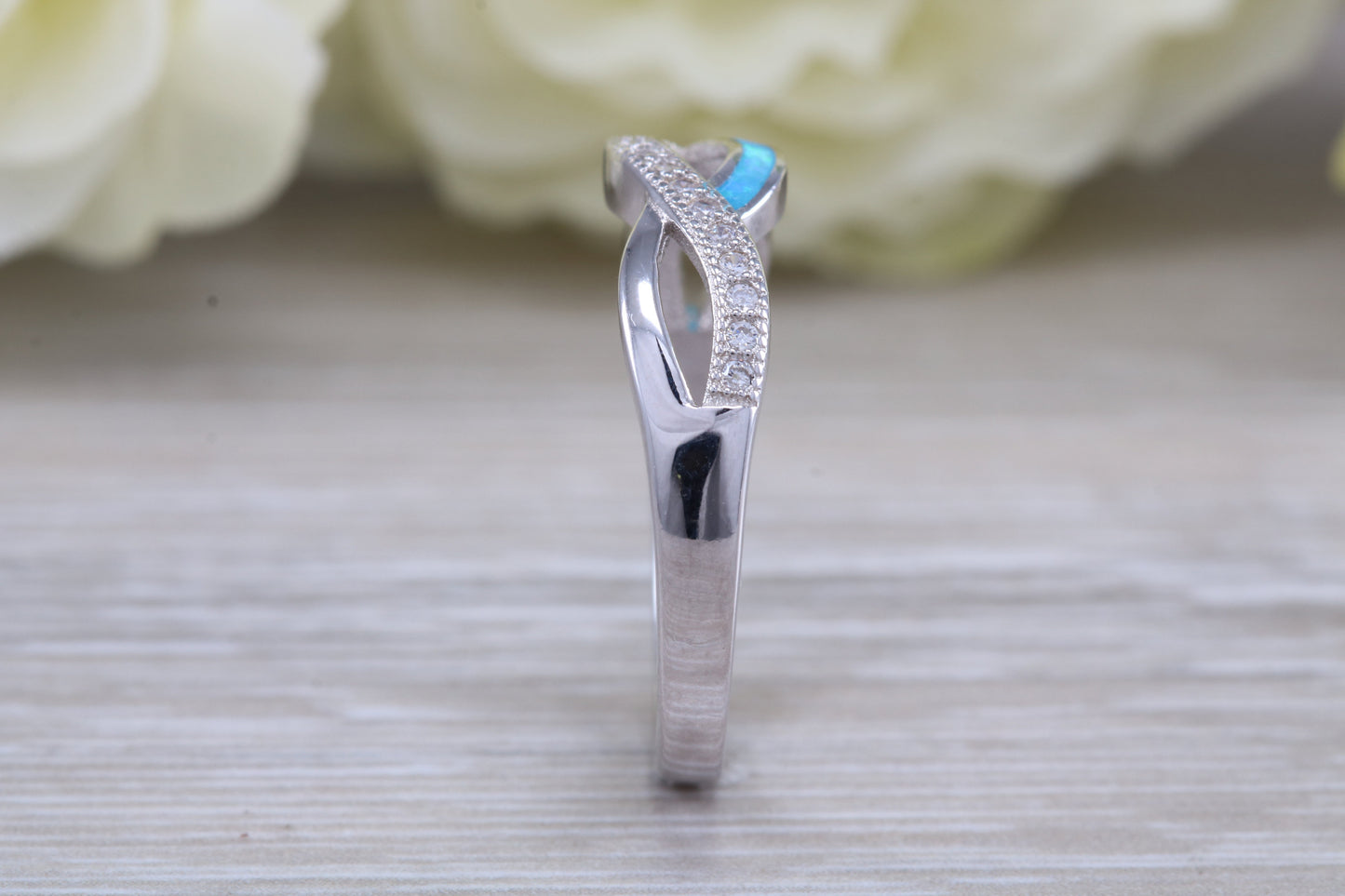 Fiery Blue Opal and cubic zirconia set cross over ring, solid sterling silver ring further rhodium plated for that platinum look