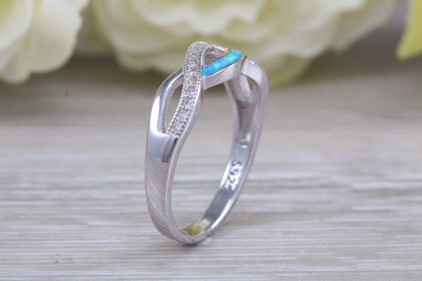 Fiery Blue Opal and cubic zirconia set cross over ring, solid sterling silver ring further rhodium plated for that platinum look